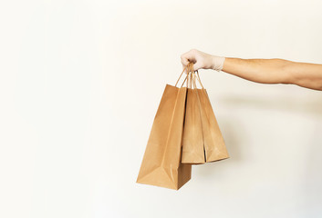 Close-up paper packages or bags holding by delivery man hand in front of white background. Food delivery service or shopping order online.