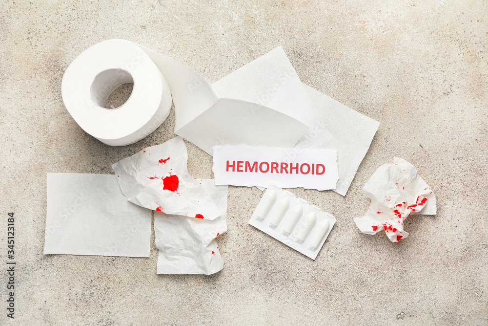 Toilet paper and hemorrhoidal suppositories on light background