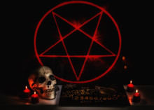 A Satanic Seance Ritual Scene With A Skull, Ouija Board, Planchette And Red Burning Candles.