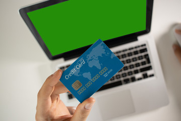 male hands holding credit card using laptop at home on the table, data security, on-line shopping. Green screen design concept.