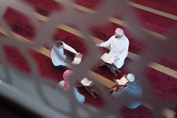 Wall Mural - Group of muliethnic religious muslim young people praying and reading Koran together inside beautiful modern mosque.