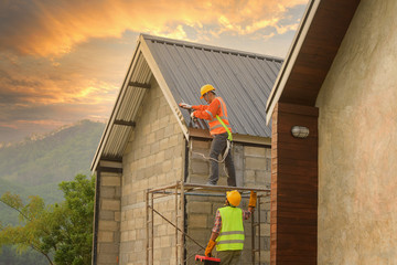 Roofer Construction worker install new roof,Roofing tools,Electric drill used on new roofs with Metal Sheet.