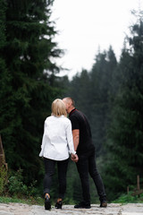 Wall Mural - A man next to a woman, guy and a girl are standing close, touching each other, holding hand on forest background. Boy and girl, couple. Intimacy, honesty, trust. Bright future. Couple