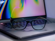 Blue Light Blocking Glasses On The Laptop. Black Frame Glasses For Filtering Blue Light From The Computer. Prevent Computer Vision Syndrome. Eye Protection From PC Screen