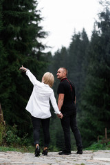 Wall Mural - A man next to a woman, guy and a girl are standing close, touching each other, holding hand on forest background. Boy and girl, couple. Intimacy, honesty, trust. Bright future. Couple