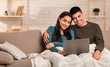 © Prostock-studio - Couple using pc sitting on the sofa with blanket