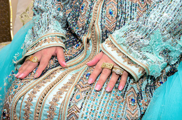  Moroccan bride wearing a blue caftan. The bride's hand is full of jewelry