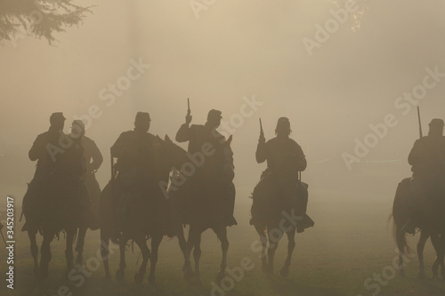 Fotografía Group of silhouetted Soldiers on Horseback with Guns in the air moving forward i