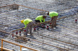 Three concrete construction workers tying rebar and setting concrete forms for building construction