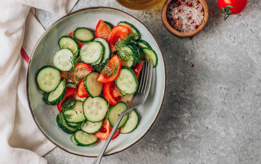 Wall Mural - Healthy vegetable salad of fresh tomato, cucumber, dill and spices and oil in bowl on light gray background. Diet concept.