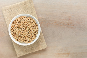 top view of roasted sunflower seeds in a ceramic dish on wooden table. alternative healthy snack concept.