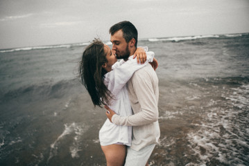 Wall Mural - Happy lovers have a cheerful vibes on sea beach at sunset 