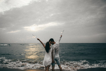 Happy lovers have a cheerful vibes on sea beach at sunset 