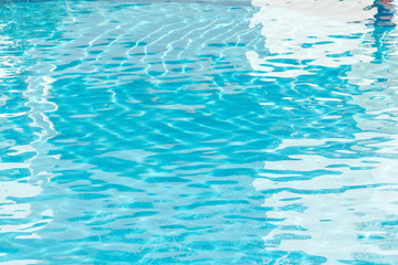 Water surface background. Blue pool water with sun reflections. Ripples of water in the pool.