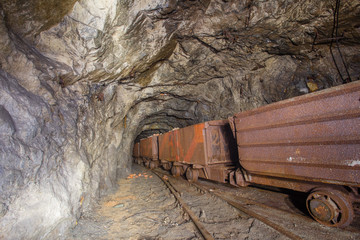 Underground abandoned iron ore mine tunnel with wagons on rails