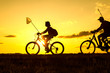Father and son returning from fishing in the evening, silhouettes of people on bicycles in nature
