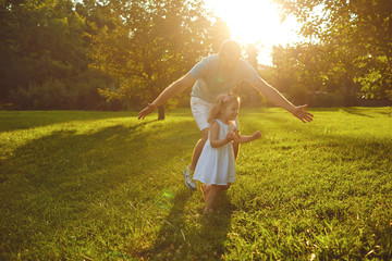 Wall Mural - Father's day. Father plays with his daughter in the summer park.