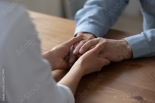 Female kind nurse or carer holding hands of elderly adult male patient giving medical care in hospice hospital or at home. Elder people healthcare, comfort and compassion, old people support concept.