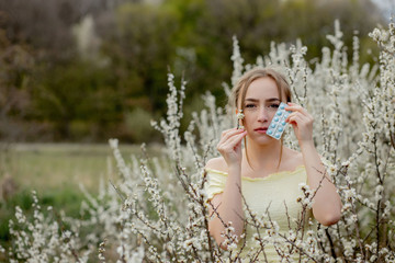 Woman with medicine in the hands Fighting Spring Allergies Outdoor - Portrait of an allergic woman surrounded by seasonal flowers