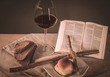 Liebevoll traditionell gestalltetes Abendmahl mit Rotwein sowie Brot und einer aufgeschalgenen Bibel , mit Kreuz. aus Holz (1. Korinther) in gelb/braunen Farbtönen.
