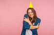 © khosrork - Fascinating girl with funny party cone hugging oneself with expression of pleasure and love, celebrating birthday alone but smiling, supporting and congratulating herself. indoor studio shot, isolated