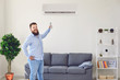 Fat funny man holding an air conditioning control panel at home. Air conditioner.