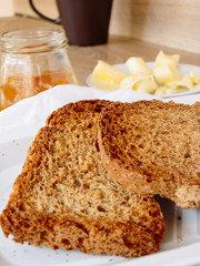 Breakfast with integral toast, butter and apricot jam on wooden table