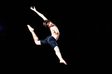 Wall Mural - Modern ballet style male dancer performs on high lighted stage .