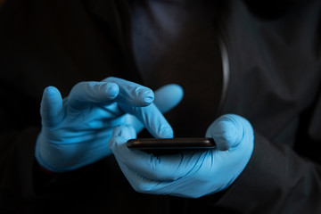 Man wearing PPE protective blue gloves use a touchscreen smartphone during Coronavirus Covid-19 outbreak. Concept for technology during pandemic