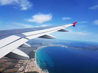 View from airplane window flying above the blue ocean