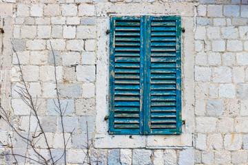 Wall Mural - Authentic house with a stone wall, with beautiful old open windows and with green shutters, and with vases on the window.