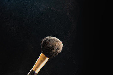 Canvas Print - The art of visage. Closeup photo of professional black makeup brush with colored powder isolated on black background