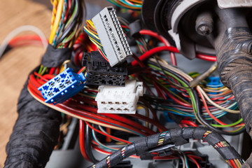 Canvas Print - Multi-colored electrical wires with connectors of white gray and blue colors in the nodes of the car rewound with insulation tape during network repair by an engineer or mechanic in a car service.