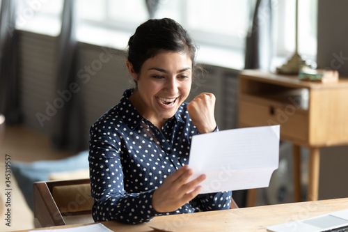 Cuadros en Lienzo Excited young indian woman holding paper document, making yes gesture, celebrating job promotion, last mortgage payment bank notification