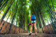 Young Woman posing in Bamboo Forest in Kyoto, Japan. Young Woman with backpack in bamboo jungle. Active lifestyle and Travel concept