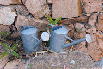 Vintage Tin Watering Can near a Wall Made of Red Stones