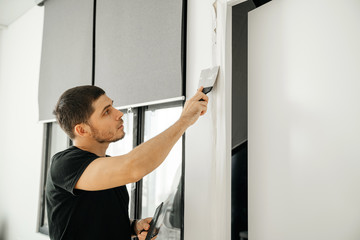 Wall Mural - The male master makes repairs in the apartment, we close up cracks in the wall in the doorway. Home repair and household chores.