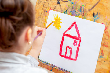 Wall Mural - Child is drawing house with watercolors on the easel.