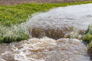 water flowing in farm field waterway after heavy rain and storms caused flooding. concept of soil er