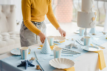 Woman Serving Party Table In Blue Colors With Textile Tablecloth, White Dishes, Glasses For Wine And Golden Cutlery. Happy Birthday Decoration.