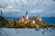 Landscape of Santa Maria Church on the alpine Bled Lake (Blejsko jezero) in autumn , Slovenia. Scenic view of the lake, island with church, Bled castle, mountains and blue sky with clouds