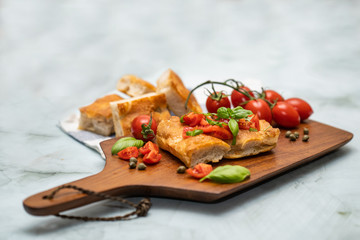 Focaccia con pomodorini pachino e basilico su tagliere di legno