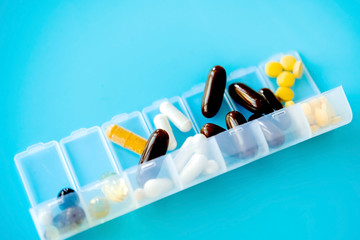 Wall Mural - Capsules lie in a pill box on a blue background. Box for packing tablets for a week.