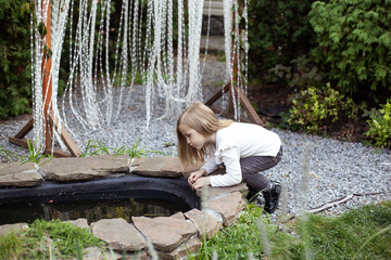 little child girl playing with pond outdoors in spring