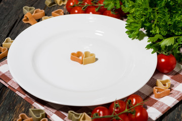 Wall Mural - table setting with white plate, pasta and vegetables on wooden background, closeup