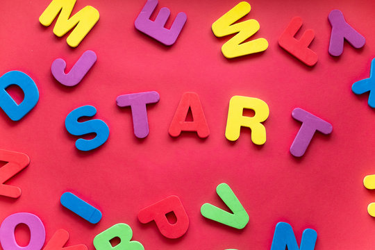 Word START From Plastic Magnetic Letters On Red Background