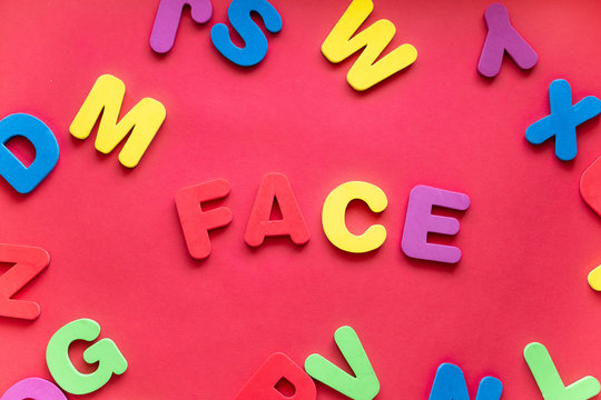 Word FACE From Plastic Magnetic Letters On Red Background