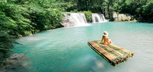 Woman In Bikini And Hat Sitting On Bamboo Raft And Enjoying View On Waterfall. Travel And Vacation Concept. Banner And Panoramic Edition.