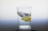 Fototapeta Łazienka - Lemon slice splash effect when falling into a glass with water