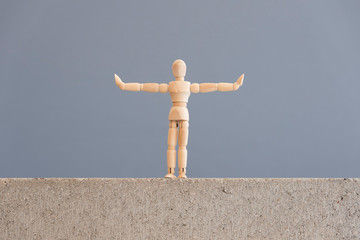 social distancing. wooden human figure standing with arms out to the sides.